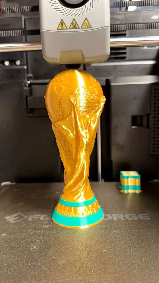Copa del mundial dorada impresa en 3D sobre la cama de la impresora