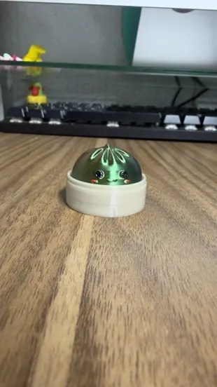 Personaje tipo dumpling metalizado verde en un bowl