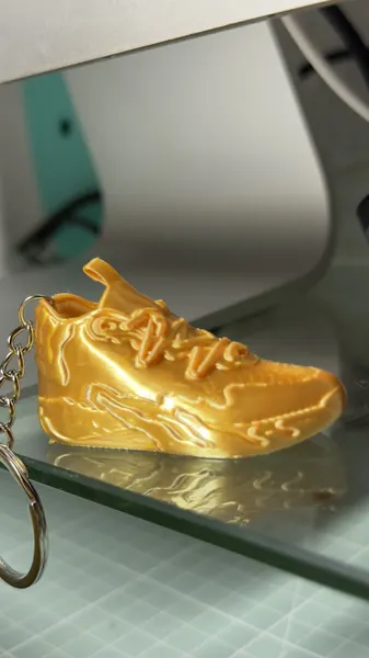 Llavero de zapatilla en filamento dorado metalizado