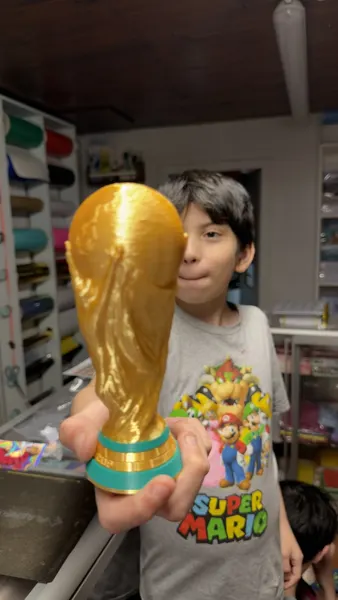 Maxi sostiene una copa del mundial impresa en 3D