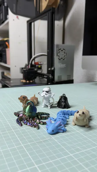 Varias figuras impresas junto a la impresora 3D